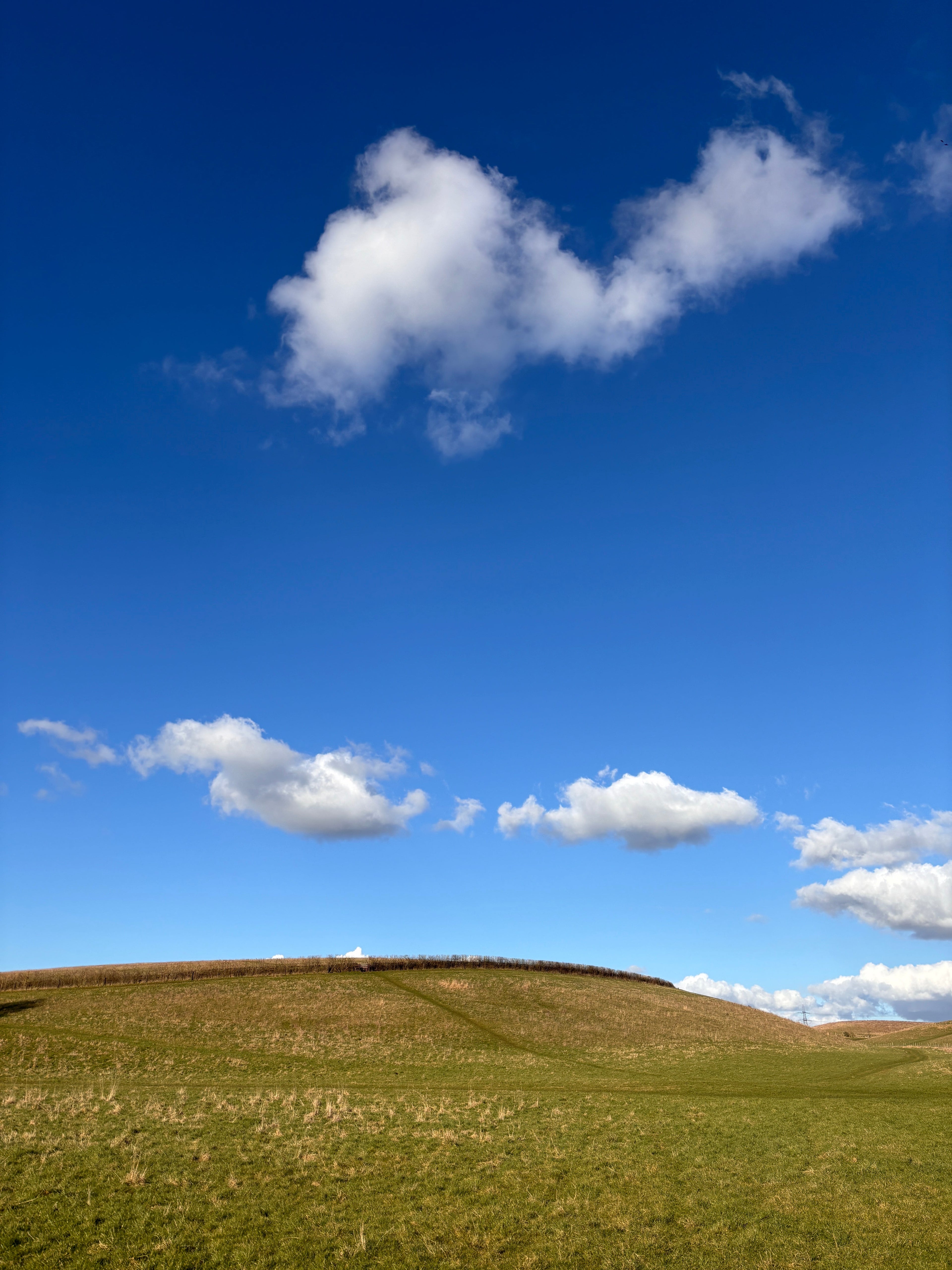 a rural countryside landscape with blue sky hills and white clouds cotswolds England